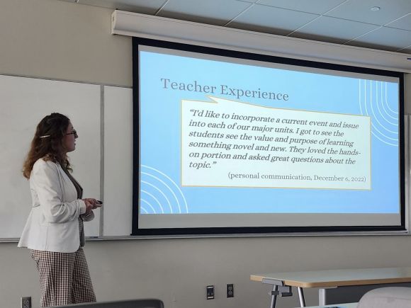 Teacher at front of classroom showing slide